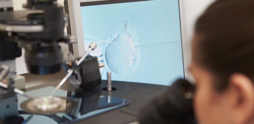 kvinde ser i mikroskop